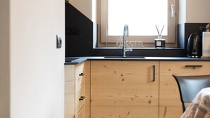 Una cucina con mobili in legno, un piano di lavoro nero, una finestra e una macchina da caffè.