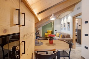 Un intérieur moderne avec un plafond en bois, une table à manger avec des chaises, un canapé et un fauteuil jaune.