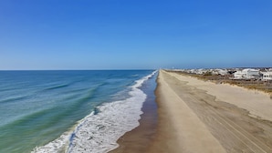 A beach with a long stretch of sand and a clear view of the ocean. - Makin' Memories! Clean, Comfortable, and Enjoyable! (Ocean Isle Beach)