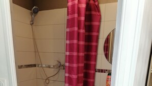 Um banheiro com chuveiro, vaso sanitário e pia.
