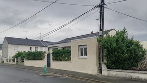Rua residencial com casas, placa de limite de velocidade e postes de eletricidade.