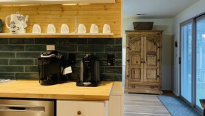 Eine Küche mit Holzarbeitsplatte, einer Kaffeemaschine, einem Wasserkocher und einem Schrank.