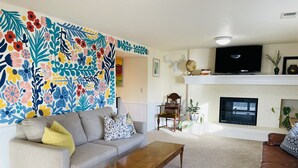 Ein Wohnzimmer mit Sofa, Couchtisch, Kamin und Fernseher.