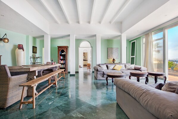A spacious living area with a dining table, sofa, and a view of the outdoors.