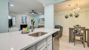 Una cocina moderna con una isla grande, electrodomésticos de acero inoxidable y un comedor con candelabro.