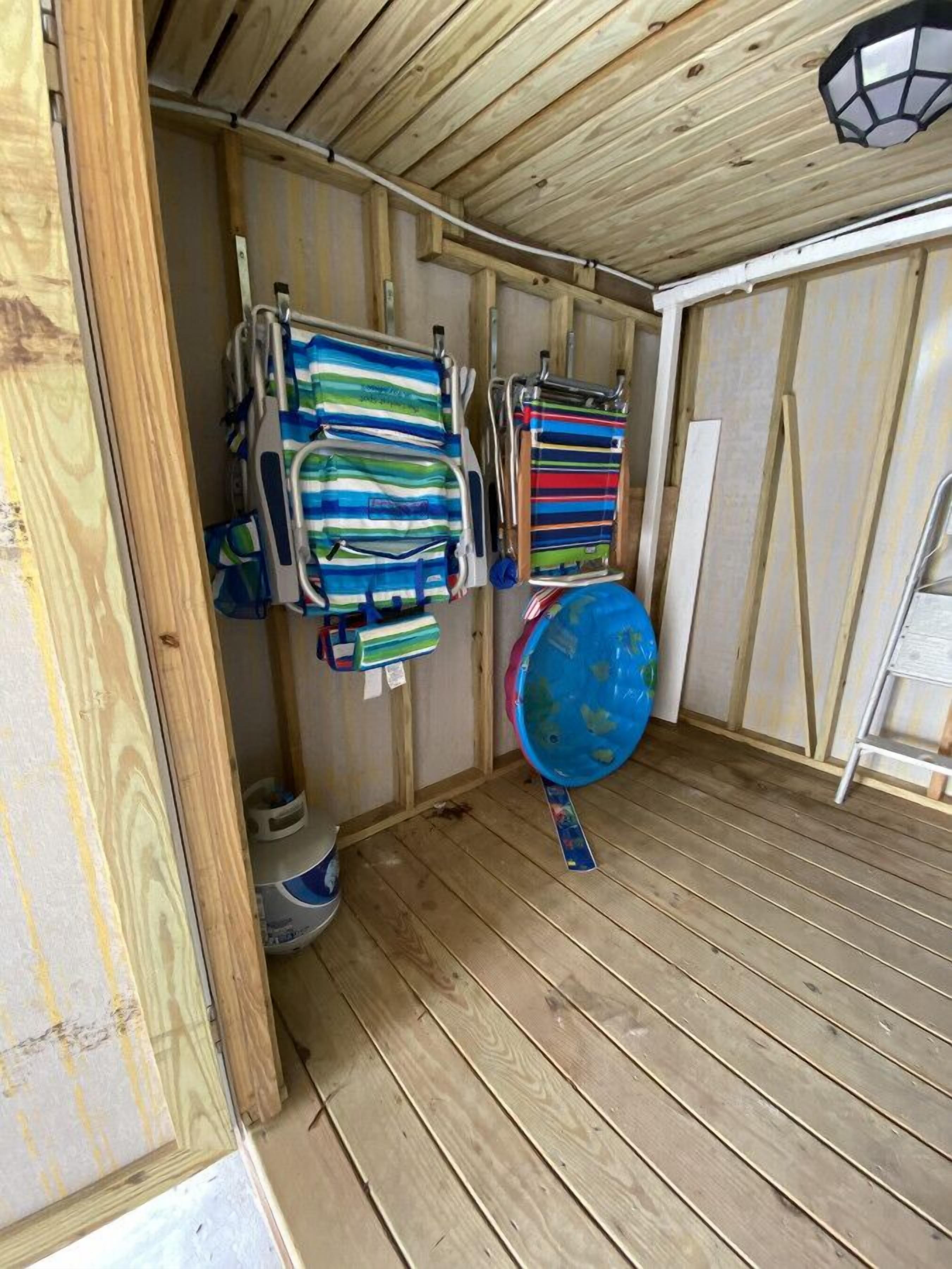 A small, enclosed wooden room with a sloped ceiling, a blue basin, and striped towels hanging on the wall.