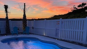 A swimming pool at sunset with a white fence and two chairs. - Impeccable home w/ pool on the desirable Ocean Ridge Drive of Atlantic Beach, NC (Atlantic Beach)