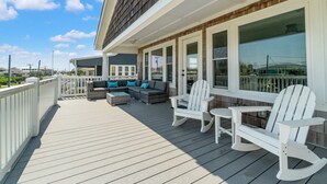 A covered deck with outdoor furniture and large windows. - Impeccable home w/ pool on the desirable Ocean Ridge Drive of Atlantic Beach, NC (Atlantic Beach)