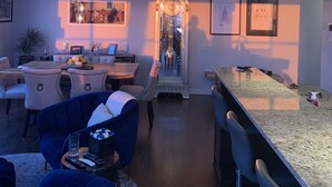 Un soggiorno moderno con zona pranzo, che include un bancone, posti a sedere e una struttura in vetro decorativa.
