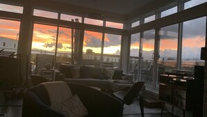 Un soggiorno spazioso con ampie finestre che offrono vista sul tramonto sulla città.