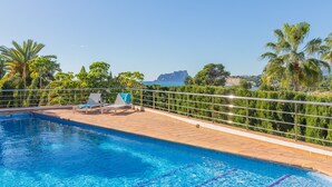 Ein Schwimmbecken mit Liegestühlen und Meerblick.