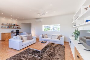 A modern living room with two white sofas, a wooden coffee table, a TV, and a bookshelf. - Villa "Casa Once Moraira" with Sea View, Pool, Garden & Wi-Fi (Moraira)