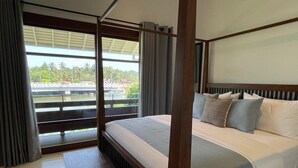 Une chambre d’hôtel avec un grand lit, une vue sur un pont et la verdure environnante, et un balcon avec des rideaux.