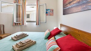 A bed with a green bedspread, red pillows, and a striped curtain. - Holiday Home "Formosa Beach" with Sea View, Terraces & Wi-Fi (Porto Santo)
