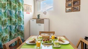 A breakfast table with plates of food, glasses of juice, and a window with a view. - Holiday Home "Formosa Beach" with Sea View, Terraces & Wi-Fi (Porto Santo)