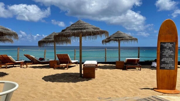 A beach with sun loungers, thatched umbrellas, and a wooden boardwalk leading to the water. - Holiday Home "Formosa Beach" with Sea View, Terraces & Wi-Fi (Porto Santo)