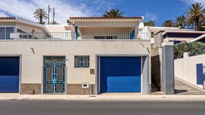 A building with a blue garage door, a gated entrance, and a balcony with a railing. - Holiday Home "Formosa Beach" with Sea View, Terraces & Wi-Fi (Porto Santo)