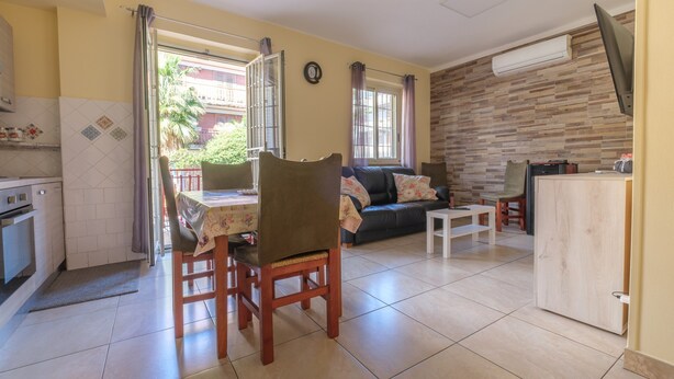 Un salon comprenant un canapé, une table à manger, des chaises, un téléviseur et un coin cuisine avec une cuisinière.
