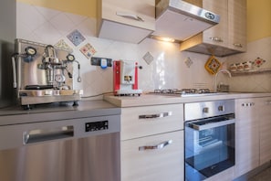 A modern kitchen with stainless steel appliances, a built-in oven, and decorative tiles on the backsplash.