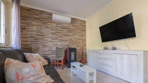 Un salon avec un canapé, une table basse, un téléviseur et une cheminée.