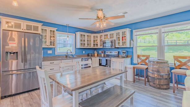 Una cocina moderna con armarios blancos, un refrigerador de acero inoxidable y una mesa de comedor de madera.