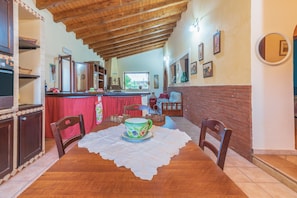 A dining area with a wooden table, chairs, a decorative cup, and a view of the kitchen and living room. - Holiday Home "Villa Gabri" with Pool, Garden & Terrace (Carlentini)