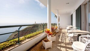 Ein Balkon mit Sitzgelegenheit im Freien, einem Geländer und Blick aufs Meer.