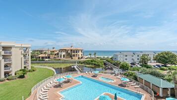 Un resort con una piscina grande, una fuente de agua y vista al océano.