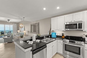 A modern kitchen with white cabinets, stainless steel appliances, and a large island with a dishwasher.
