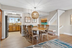 A dining area with a round table, wooden chairs, and a hanging light fixture.