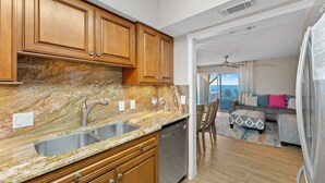 A kitchen with granite countertops, wooden cabinets, and a stainless steel sink. - Gulf Front Townhome, Downtown Destin! (Destin)
