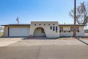 A single-story building with a garage, an arched entryway, and a small porch area. - Bullhead City Home - Near Colorado River! (Bullhead City)