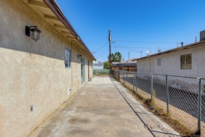 A narrow concrete pathway flanked by buildings with chain-link fences, utility poles, and satellite dishes. - Bullhead City Home - Near Colorado River! (Bullhead City)