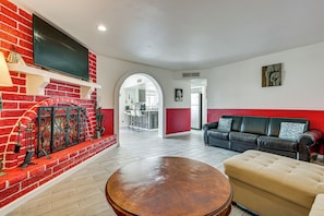 A living room with a fireplace, a sofa, a coffee table, and a television. - Bullhead City Home - Near Colorado River! (Bullhead City)