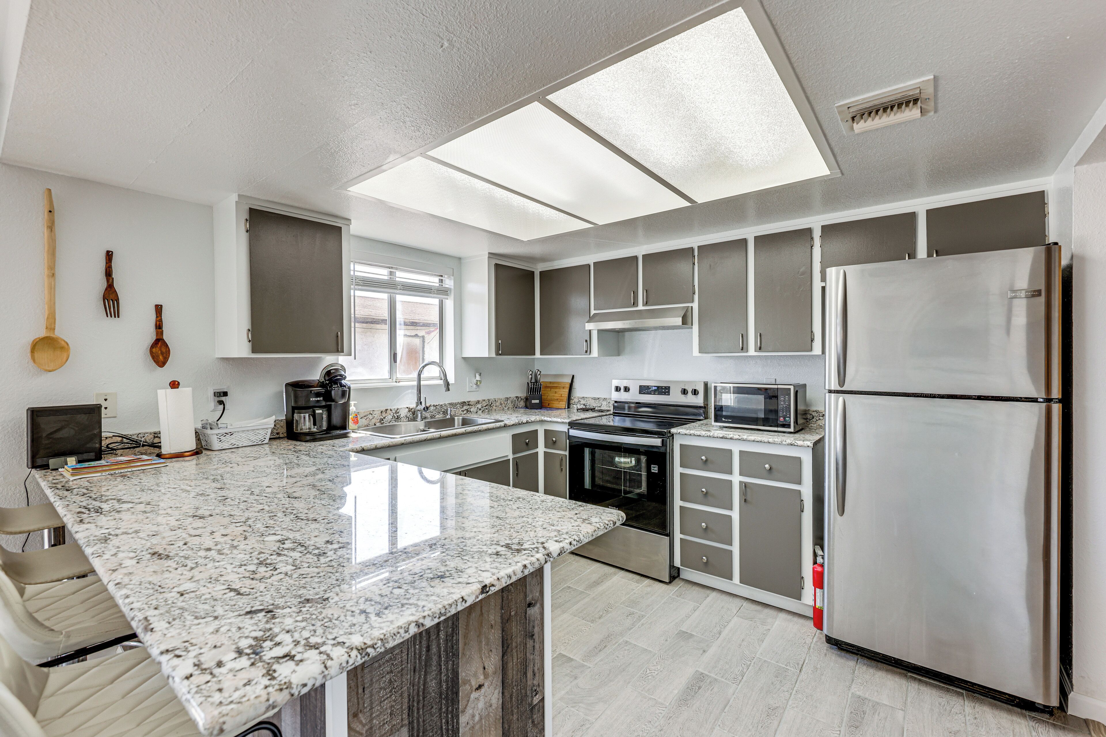 A modern kitchen with a large island, stainless steel appliances, and a window providing natural light.