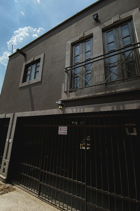 A building with a gated entrance, a balcony, and a sign indicating restricted access hours.