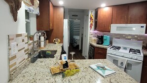 Une cuisine dotée de plans de travail en granit, d’une cuisinière blanche et d’un poisson suspendu.