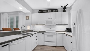 A modern kitchen with white cabinetry, a microwave, an oven, and a dishwasher.