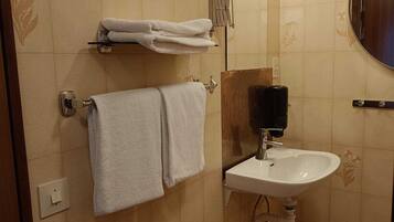 A bathroom with a white sink, a towel rack with folded towels, a mirror, and a light fixture.