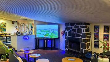 Ett mysigt loungeområde med en platt-TV, bekväma sittplatser, en öppen spis i sten och en bardisk med en neonreklamskylt.