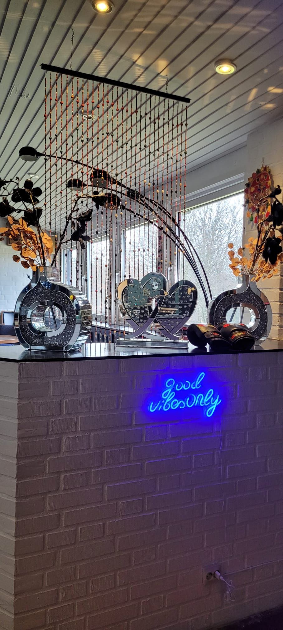 A reception desk with a neon sign, a hanging decorative piece, and a brick wall.