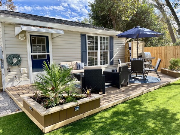 A patio area with outdoor furniture, a grill, and a wooden deck.