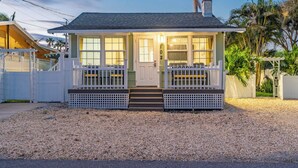 Ein kleines, eingeschossiges Haus mit Veranda, Hausnummer '102' an der Tür und einem Schotterweg.