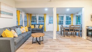 Ein Wohnzimmer mit Sofa, Couchtisch und Essbereich mit Stühlen und Tisch.