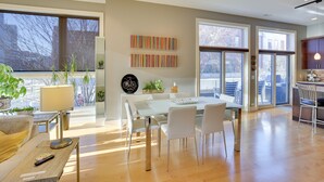 Un soggiorno moderno con zona pranzo, ampie finestre e cucina.