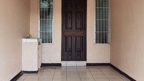 A room with a tiled floor, a door with a metal grill, and a small cabinet with a faucet. - Lara Loft 5 minutes from Juan Santa María Airport (Alajuela)