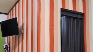 A room with striped walls, a black door, and a mounted television. - Lara Loft 5 minutes from Juan Santa María Airport (Alajuela)
