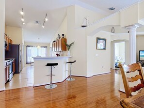 A spacious kitchen with a central island, wooden flooring, and modern lighting fixtures.