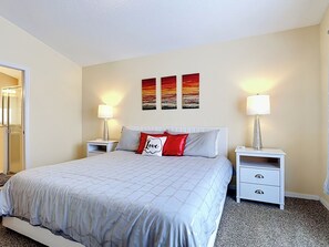 Una habitación de hotel con una cama grande, dos mesitas de noche y una puerta que da a un baño.