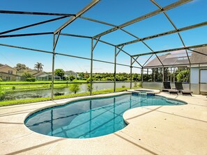 A swimming pool with a curved design, surrounded by a covered area with lounge chairs.